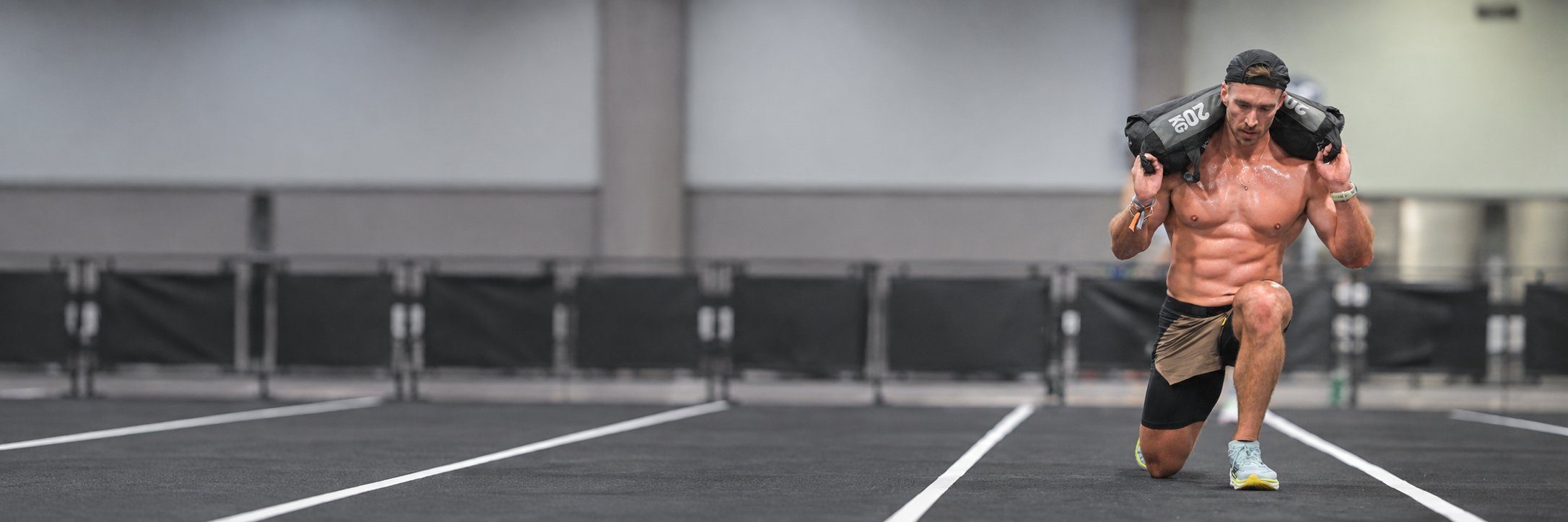 Athlete doing sandbag lunges on a HYROX race floor